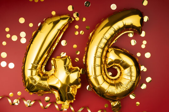 46th birthday celebration. Gold festive balloons number 46 year anniversary on red background with confetti. Birthday or wedding event.