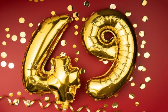 49th birthday celebration. Gold festive balloons number 49 year anniversary on red background with confetti. Birthday or wedding event.