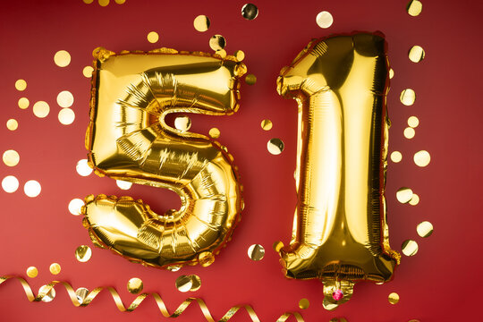 51st birthday celebration. Gold festive balloons number 51 year anniversary on red background with confetti. Birthday or wedding event.