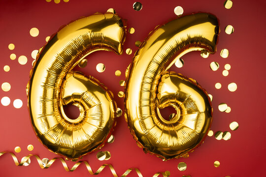 66th birthday celebration. Gold festive balloons number 66 year anniversary on red background with confetti. Birthday or wedding event.