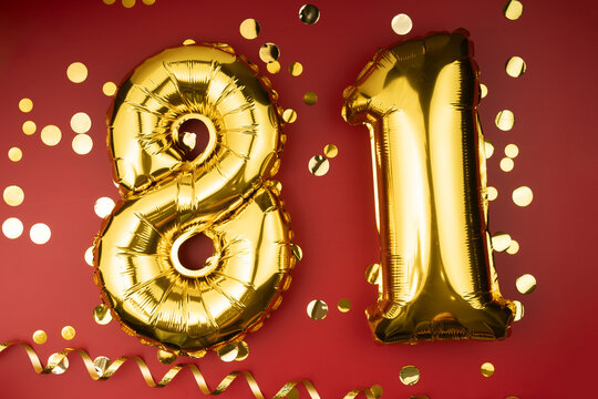 81st birthday celebration. Gold festive balloons number 81 year anniversary on red background with confetti. Birthday or wedding event.