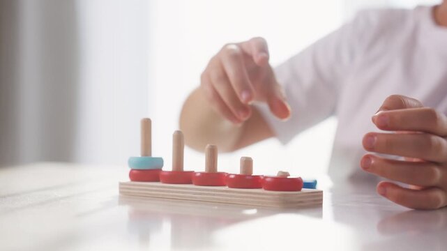 Child plays with toy r rings pyramid on table in kindergarten. Fun lifestyle childhood leisure. concept. The child masters fine motor. skills. Child masters fine motor skills, educational game.