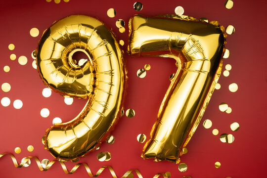 97th birthday celebration. Gold festive balloons number 97 year anniversary on red background with confetti. Birthday or wedding event.