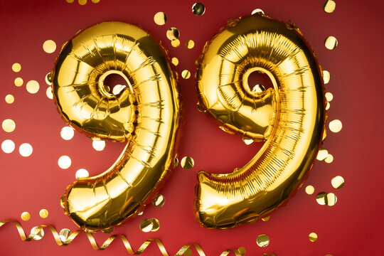 99th birthday celebration. Gold festive balloons number 99 year anniversary on red background with confetti. Birthday or wedding event.