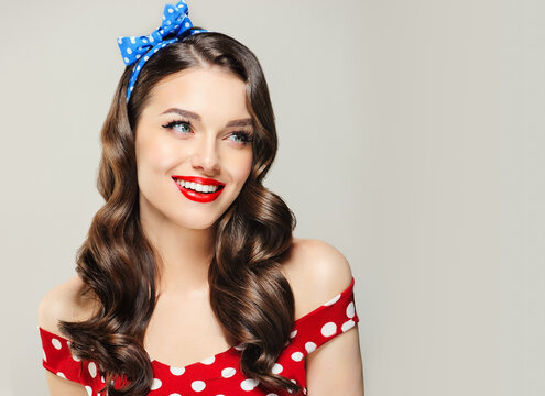 A Pin Up smiling young woman in a retro outfit  showcasing an invisible Presenting your product .Beautiful smile vintage girl with curly hair  .Expressive facial expressions. wavy hairstyle