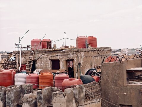 Basra, Iraq - April 06, 2026: Rows of colorful plastic water storage tanks on an urban rooftop.