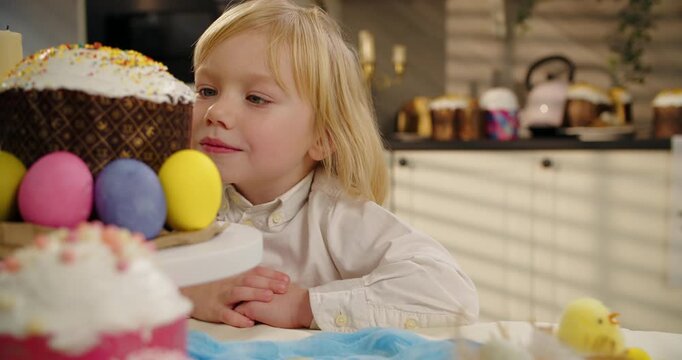 Little boy looking at Easter cake and colored eggs