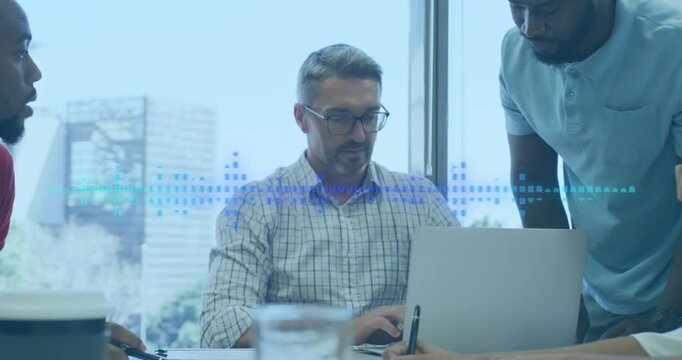Two colleagues are talking and using a laptop in a modern office