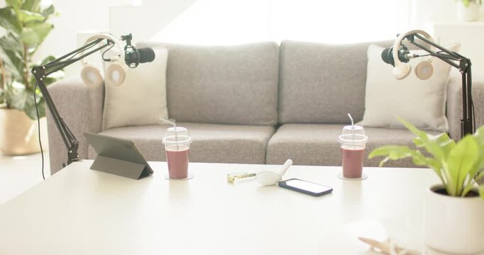 Tabletop near sofa is holding mics while window light and breeze are nudging leaves and straws