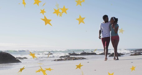 Strolling couple wearing striped shirt, teal top on wet sand near waves, golden stars, copy space © vectorfusionart