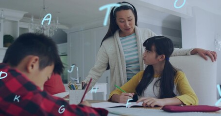 Obraz premium Leaning mid adult woman guiding girl in yellow top at kitchen table, with green pencil