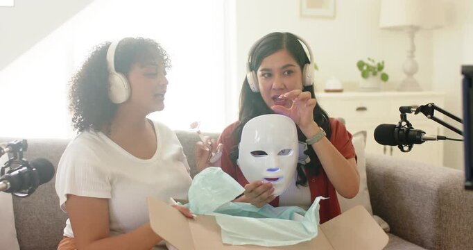Two hosts opening box and unboxing LED facial mask, demonstrating glowing lights for product review