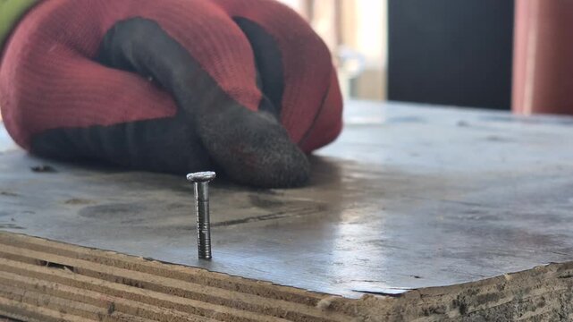 Slow motion extreme close-up of a hammer hitting a nail into a wooden formwork box.