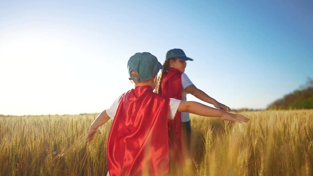 A group of kids playing a video game of superheroe together. Child hero fun concept. Superhero running through the sunset wheat with. children. A group of kids playing a game of running together.