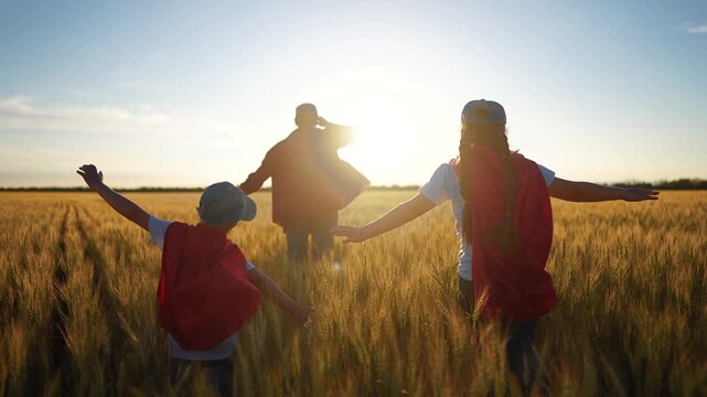 Superhero running through the wheat with his family. Child group superhero family concept. group of children are running together in a field. Superheroes run field of wheat children fun together.