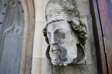 Obraz premium Weathered Stone Carved Head on Historic Church Exterior