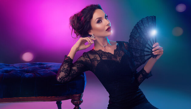 Kobieta na r&oacute;żowym tle w koronkowej bluzce i trzymająca wachlarz