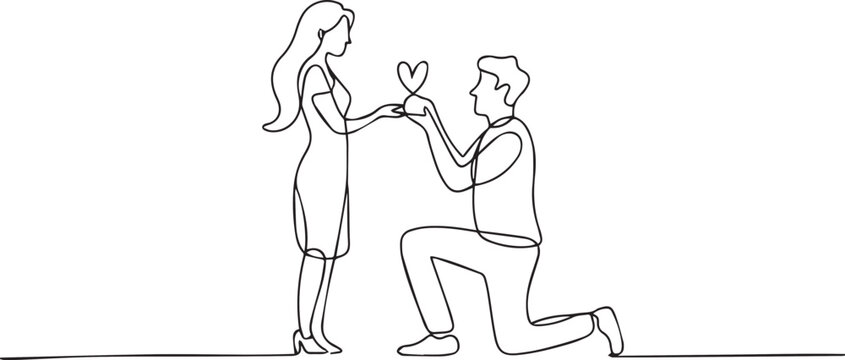 Man proposing to woman with heart shaped gift on one knee in love