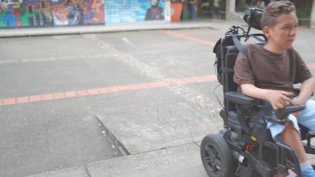 Independent Young Man in a Power Wheelchair Navigating Up a Concrete Access Ramp at University