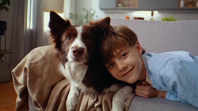 Boy rests near dog smiling in close sofa moment at home