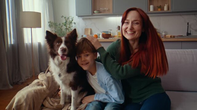 Woman hugs boy and dog during joyful moment on sofa at home