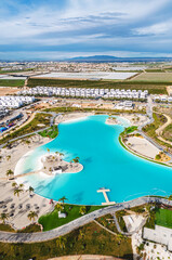 Aerial view of modern resort community with turquoise lagoon swimming pool, residential apartment buildings, landscaped gardens, and palm trees. Murcia, Spain © Alex Tihonov