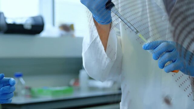 Lab researcher receiving tube and fitting pipette tip, aspirating orange liquid during sample prep