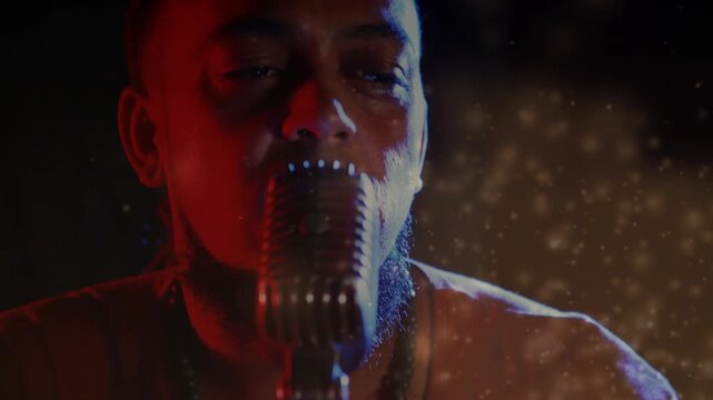 Male singer leaning into vintage mic as camera pulls back, singing with red bokeh framing face