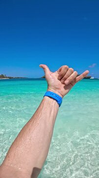POV of an adult man in transparent turquoise water with green rocky islands under a blue sky in Watamu, Kenya.
