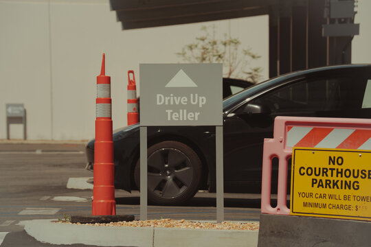 Drive up teller sign with car and traffic cones in a parking lot