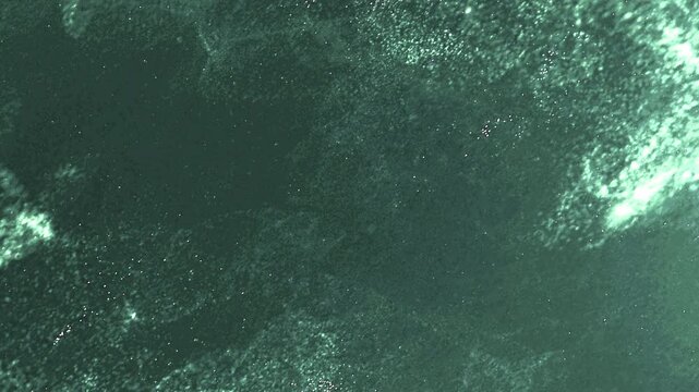 Particles dark green ocean water with sunlight filtering through the surface, creating a mesmerizing pattern of light and shadow.