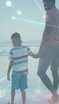 Vertical video: HUD starting, dad and son walking to sea holding hands, son pausing at surf bonding