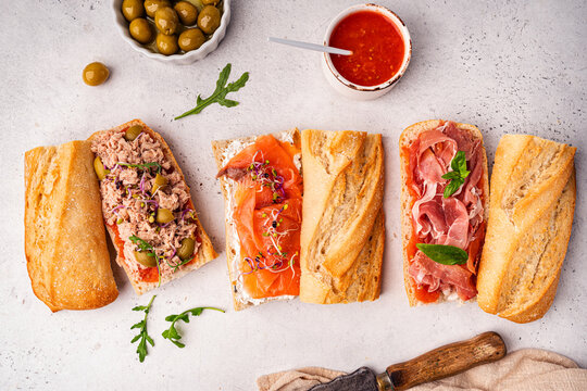 Variety of sandwiches with tuna, salmon y jamon or prosciutto for breakfast on white background, top view, Bruschetta snacks for wine.