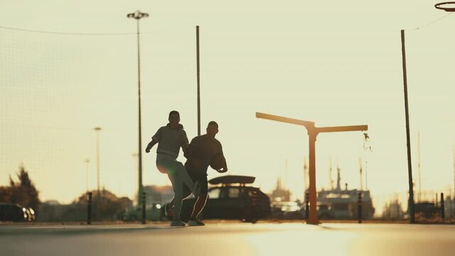 Silhouette of friends playing basketball outdoor at sunset