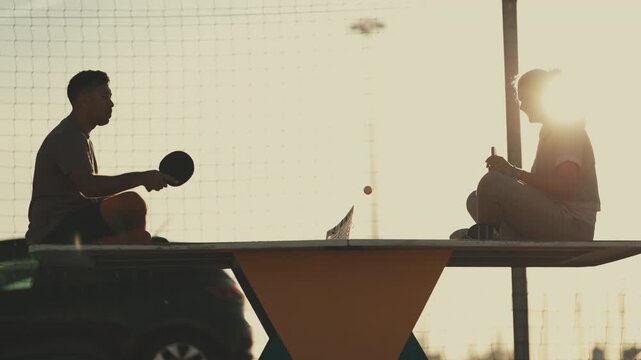 Couple sitting on table playing ping pong