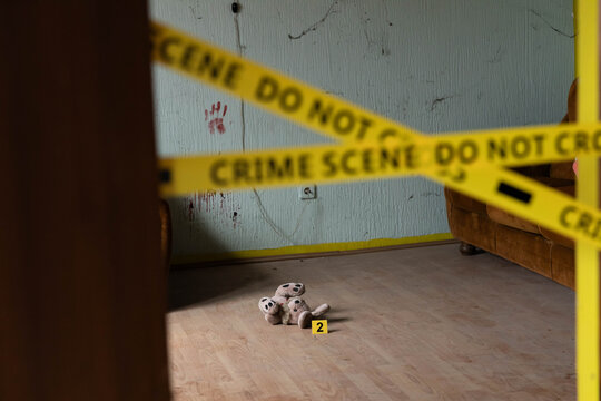 A teddy bear positioned within a crime scene, representing the loss of innocence in a violent setting.