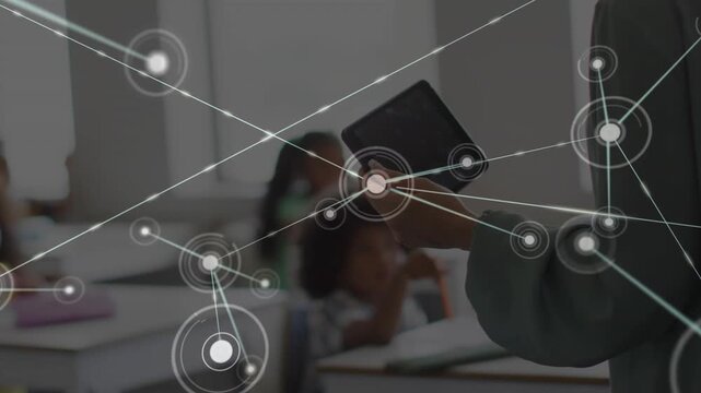 Teacher holding tablet, tilting and activating nodes and lines from tablet, teaching networks