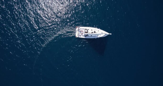 White Vessel In Vast Sea. Isolated White Yacht Charted Against Deep Ocean. Vivid Snapshot Of Single Yacht Navigating Deep Blue Waters With Sparkling Surface