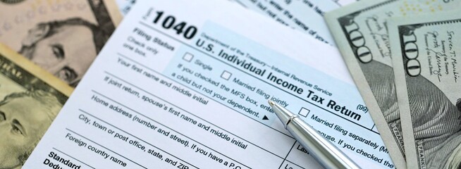 Obraz premium 1040 Individual Income tax return form and pen with dollars money bills on accountants table