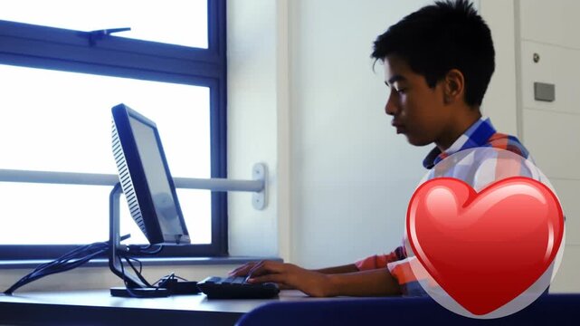 Red heart icon with copy space against indian boy using computer at school