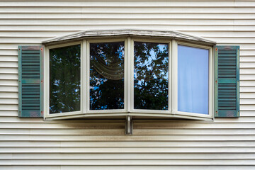 Fototapeta premium Classic bay window with green shutters on a light-colored vinyl siding house wall, Boston, Massachusetts 