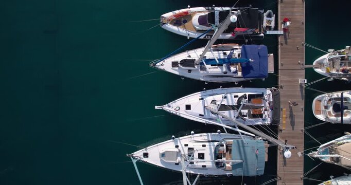 Overhead Marina Berths With Boats Lined Along Wooden Jetty, Varied Hulls And Masts Forming Geometric Pattern, Calm Green Water And Leisurely Atmosphere For Nautical