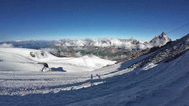 Pan shot of mountain glacier panorama with summit Gran Paradiso and Matterhorn seen from Klein Matterhorn in summer in Swiss Alps, canton of Valais, Switzerland