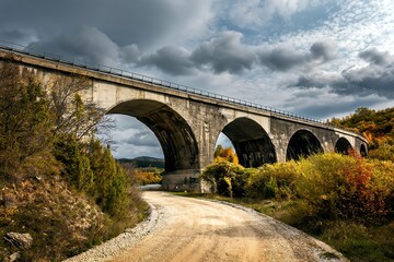 Fototapeta premium Arch bridge on Zlatibor mountain in Serbia. Autumn landscape with colorful leaves at sunset. 