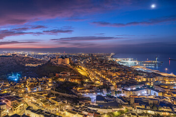Fototapeta premium Panoramic night cityscape of Almeria featuring Alcazaba fortress harbor and urban districts illuminated