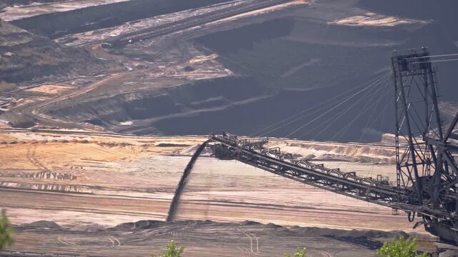 Heavy mining machine dropping sand on a open lignite coal mine, static slow motion