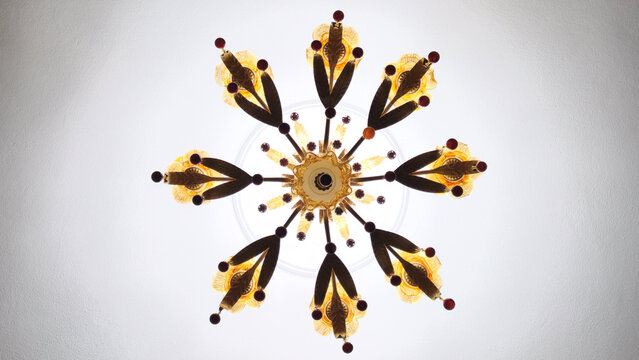 Under view of a chandelier in a warm classic style with a brass or bronze appearance, featuring glass details and decorative hanging elements
