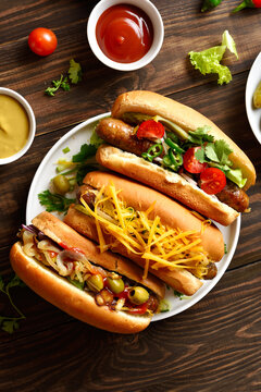 Hot dogs with different toppings on wooden table