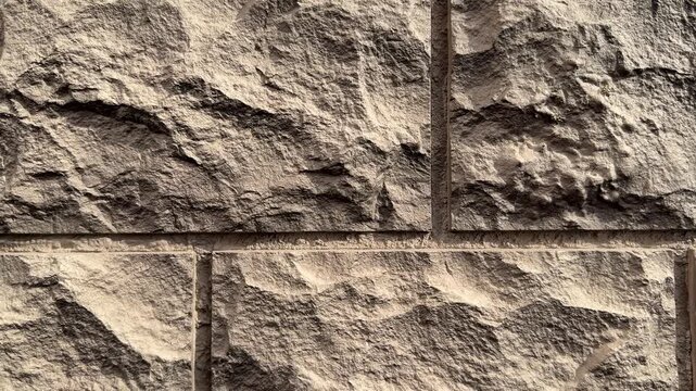 Facade panel closeup showing rugged stone texture and mortar lines on beige sandstone blocks, dramatic shadow play, ideal.