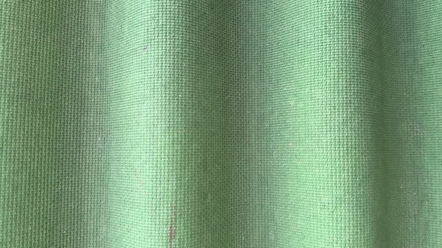 Green corrugated roofing tile closeup showing wavy fibrous surface and weatherproof bitumen texture, macro studio lit study.